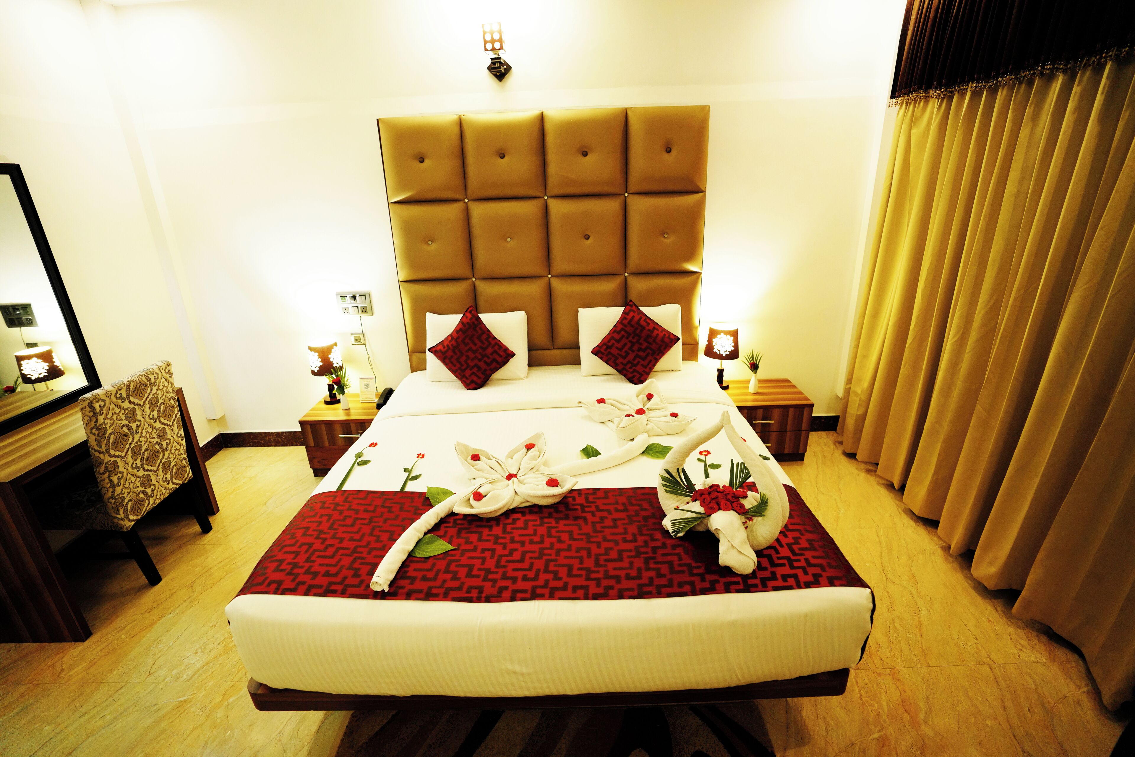 Habitación de hotel con una cama grande, dos mesitas de noche, un cabecero y una ventana con cortinas.