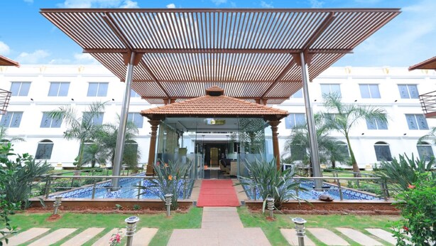 A hotel entrance with a covered walkway, palm trees, and a red carpet leading to the entrance. - Jal Mahal Resort & Spa, Mysore (Mysore)