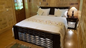 Un dormitorio con una cama, una mesita de noche, una lámpara y un teléfono instalado en la pared.