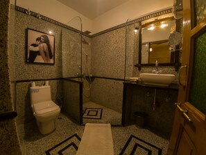 Un baño con inodoro, ducha, lavamanos y un cuadro en la pared.