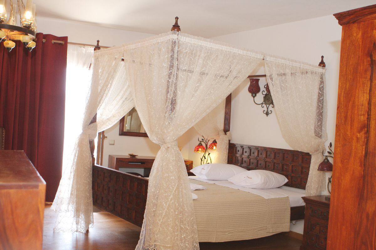A bedroom with a four-poster bed, wooden headboard, and a canopy.