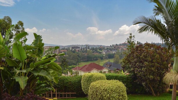 A residential area with well-maintained gardens, a clear view of houses, and a distant cityscape. - Golf Hills Residence Hotel (Kigali)