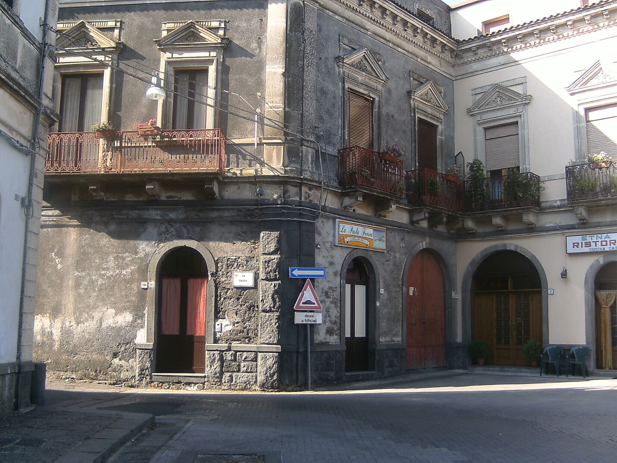Un edificio histórico con fachada de piedra, múltiples balcones y puertas arqueadas.