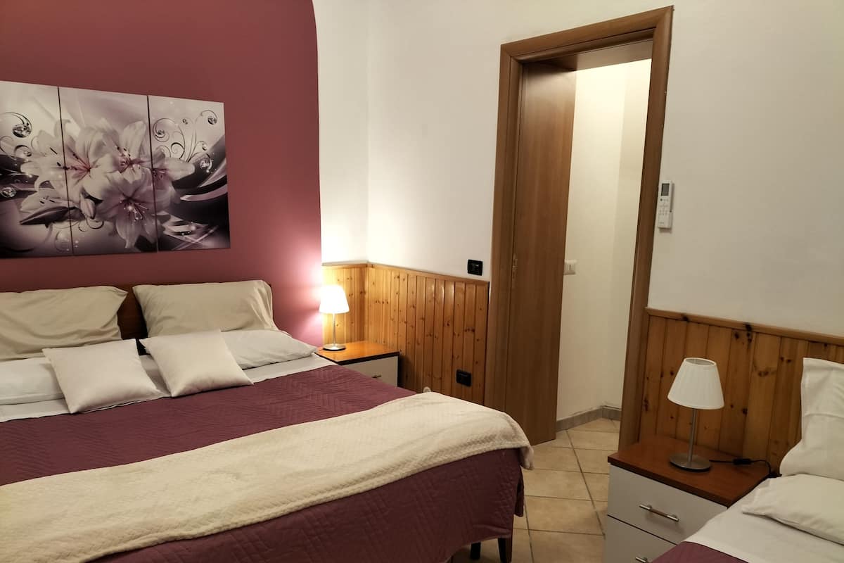 Ein Schlafzimmer mit Bett, Nachttischen, einer Lampe und einer Tür.