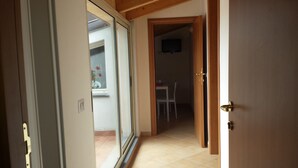 An open door leading to a room with a tiled floor, a white table, and a chair. - Da Rosa (Linguaglossa)