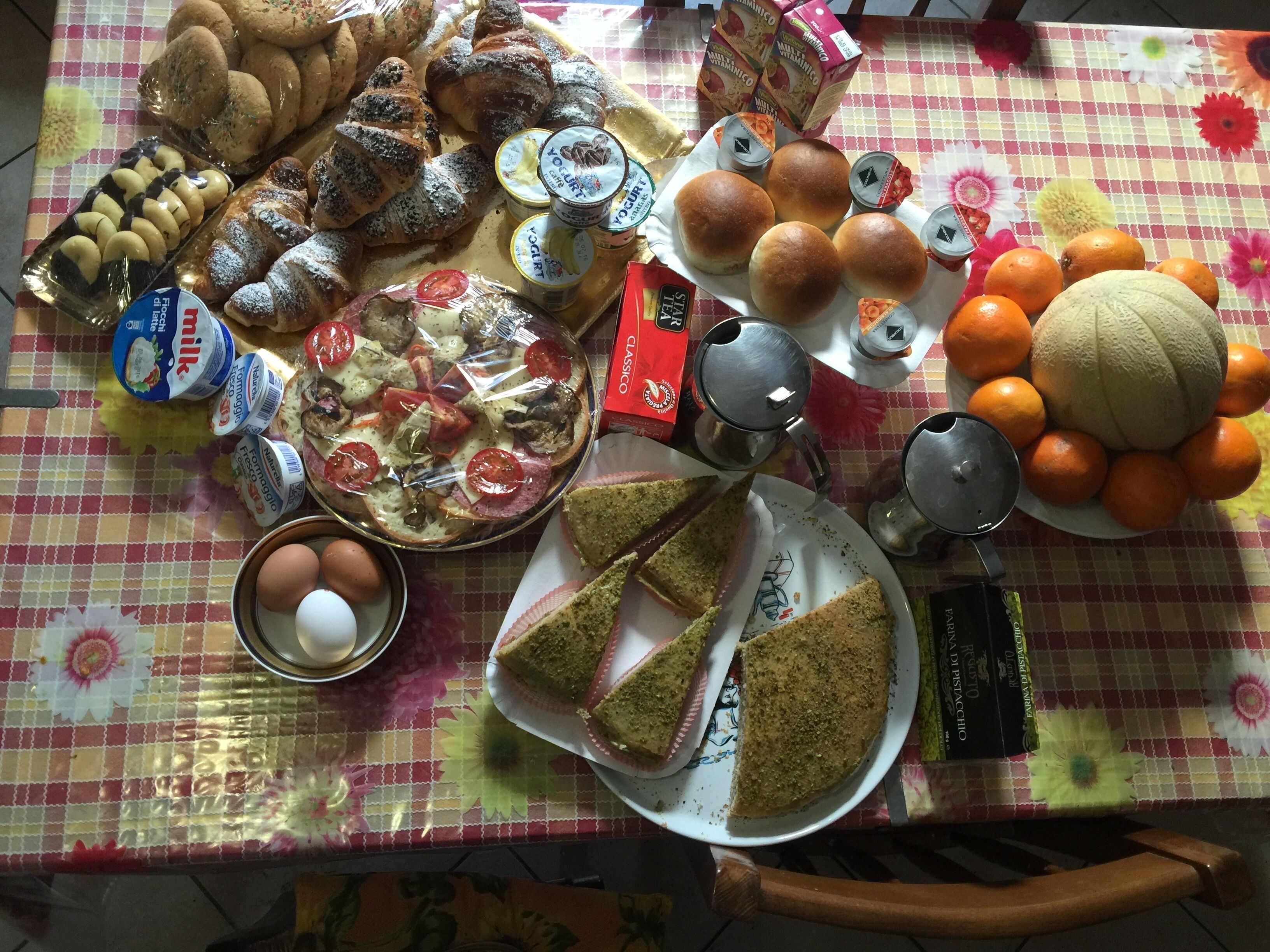 Une table garnie de divers aliments, notamment du pain, des pâtisseries, du fromage et des fruits.