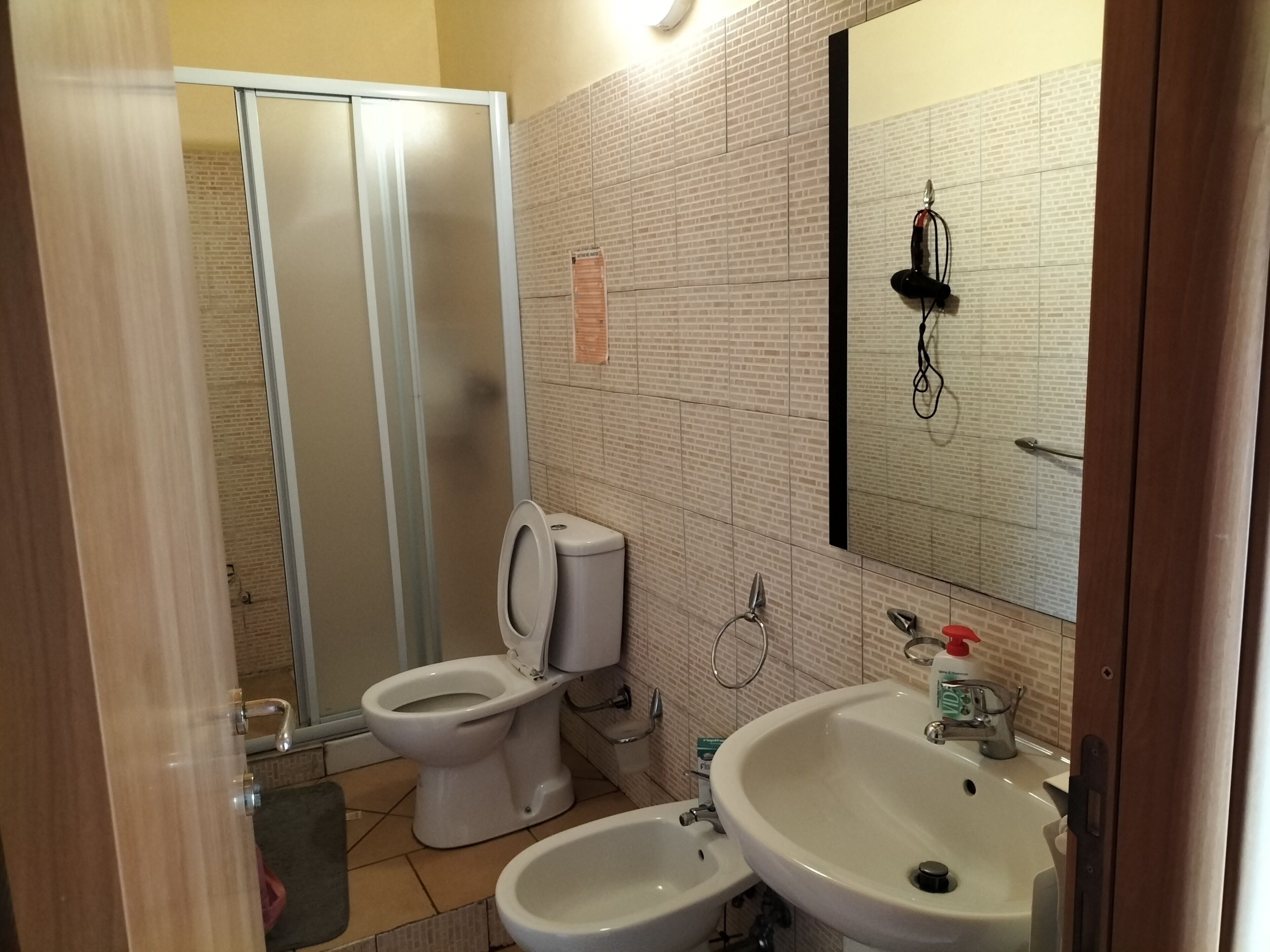 Un baño con inodoro, bidé, lavamanos y espejo.