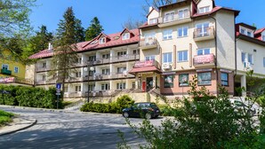 A multi-story hotel with balconies, a red roof, and a sign for a pension.
