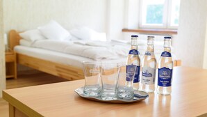 A wooden table with three glasses and three bottles of water in a hotel room.
