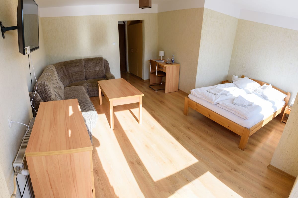 Um quarto com uma cama, um sofá, uma mesa de madeira e uma escrivaninha com uma cadeira.