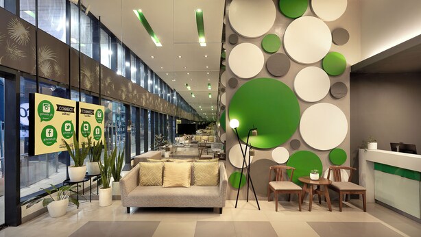 Una hall moderna con reception, area salotto e piante in vaso.