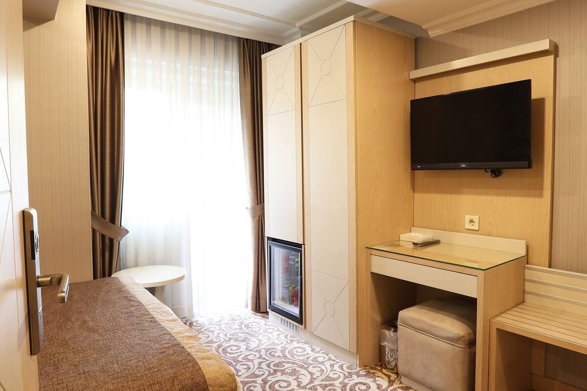 A hotel room with a bed, a desk, a television, and a bathroom.