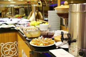 Buffet-pöytä, jossa on monipuolinen valikoima ruokia, sekä kahviautomaatti.