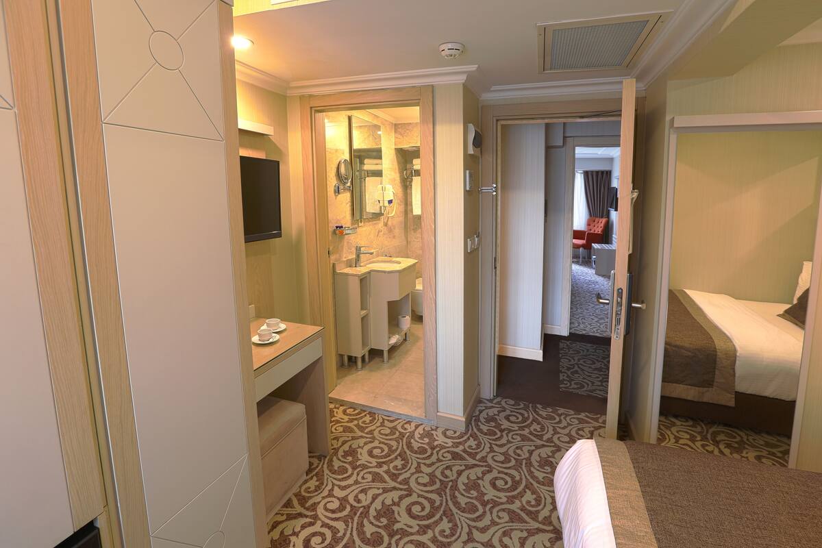 A hotel room with a bathroom, a bed, a desk, and a TV.