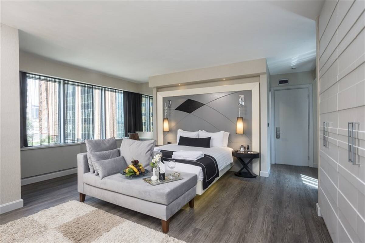 Une chambre d’hôtel moderne, équipée d’un lit, d’un canapé, d’une table de chevet et d’une grande fenêtre.