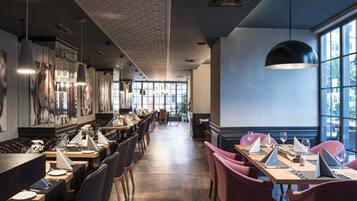 Un restaurante moderno con suelo de madera, mesas largas e iluminación colgante.