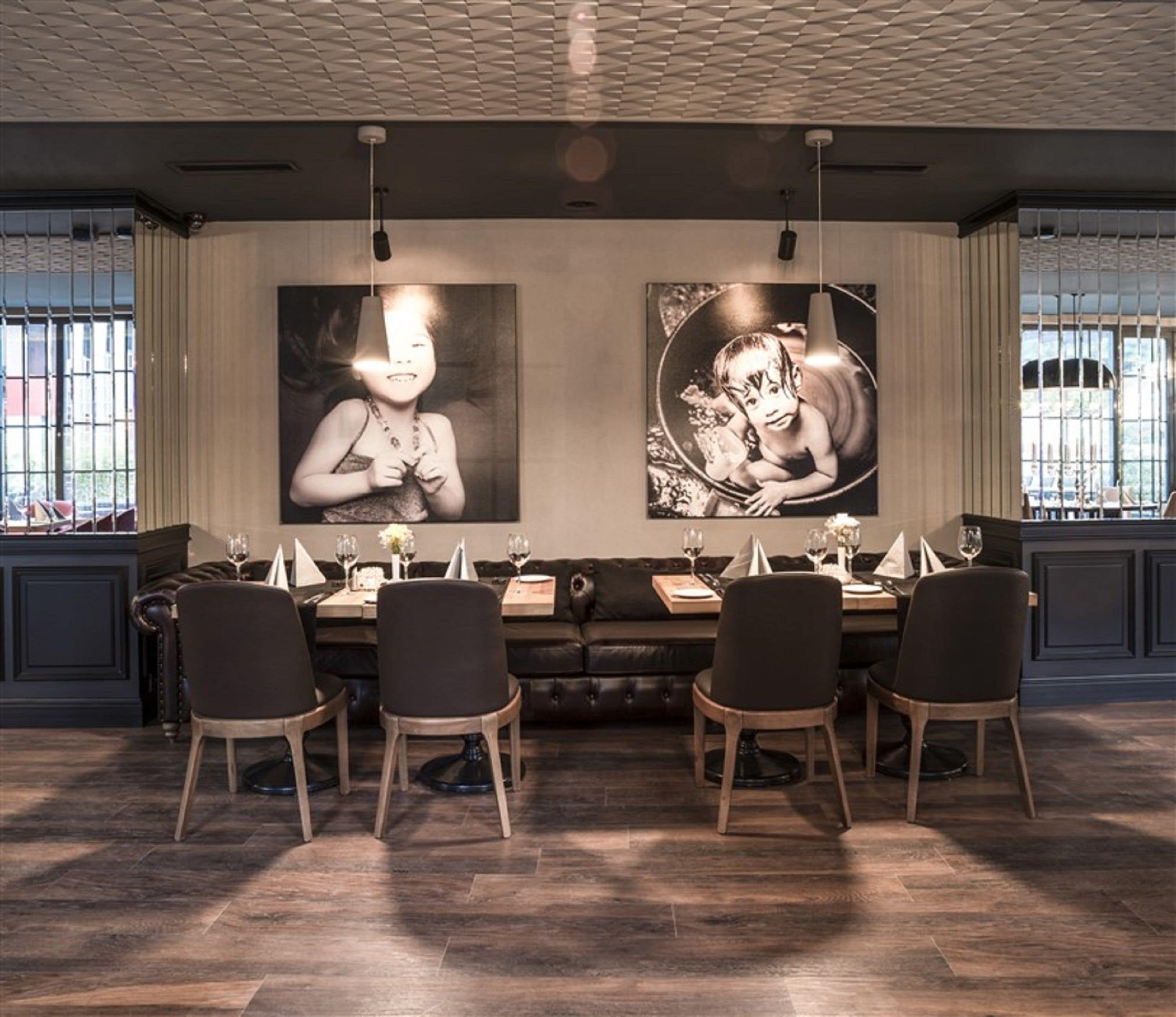 A dining area with a long table, four chairs, and two large wall-mounted paintings.