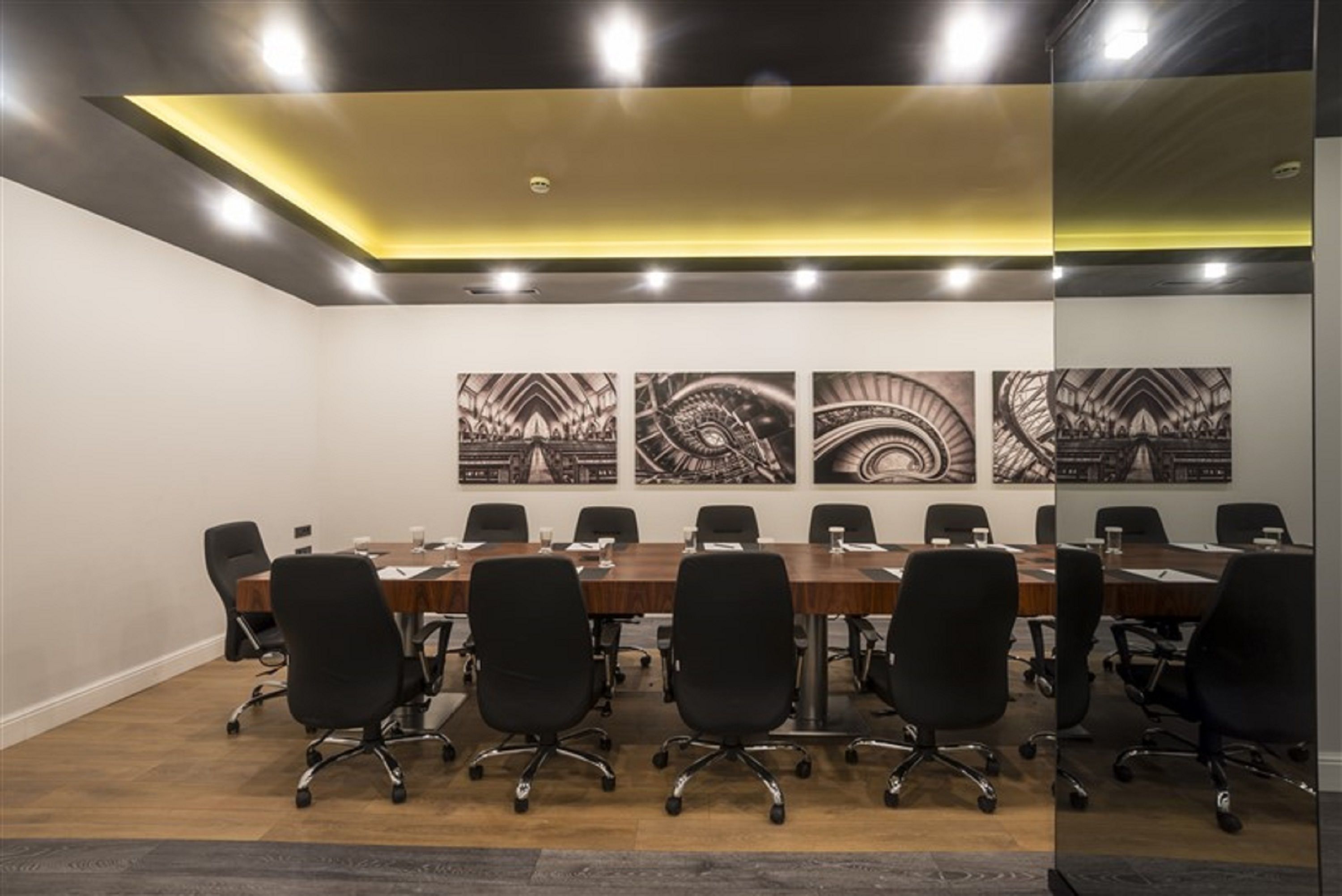 Una sala de conferencias con una larga mesa, sillas de oficina negras y cuatro grandes obras de arte blanco y negro en la pared.