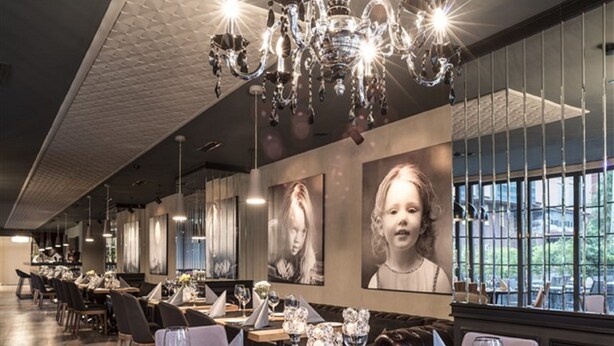 Un restaurant doté d’un lustre, de tables rondes et de portraits encadrés accrochés aux murs.
