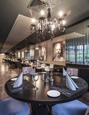 Un restaurant doté d’un lustre, de tables rondes et de portraits encadrés accrochés aux murs.