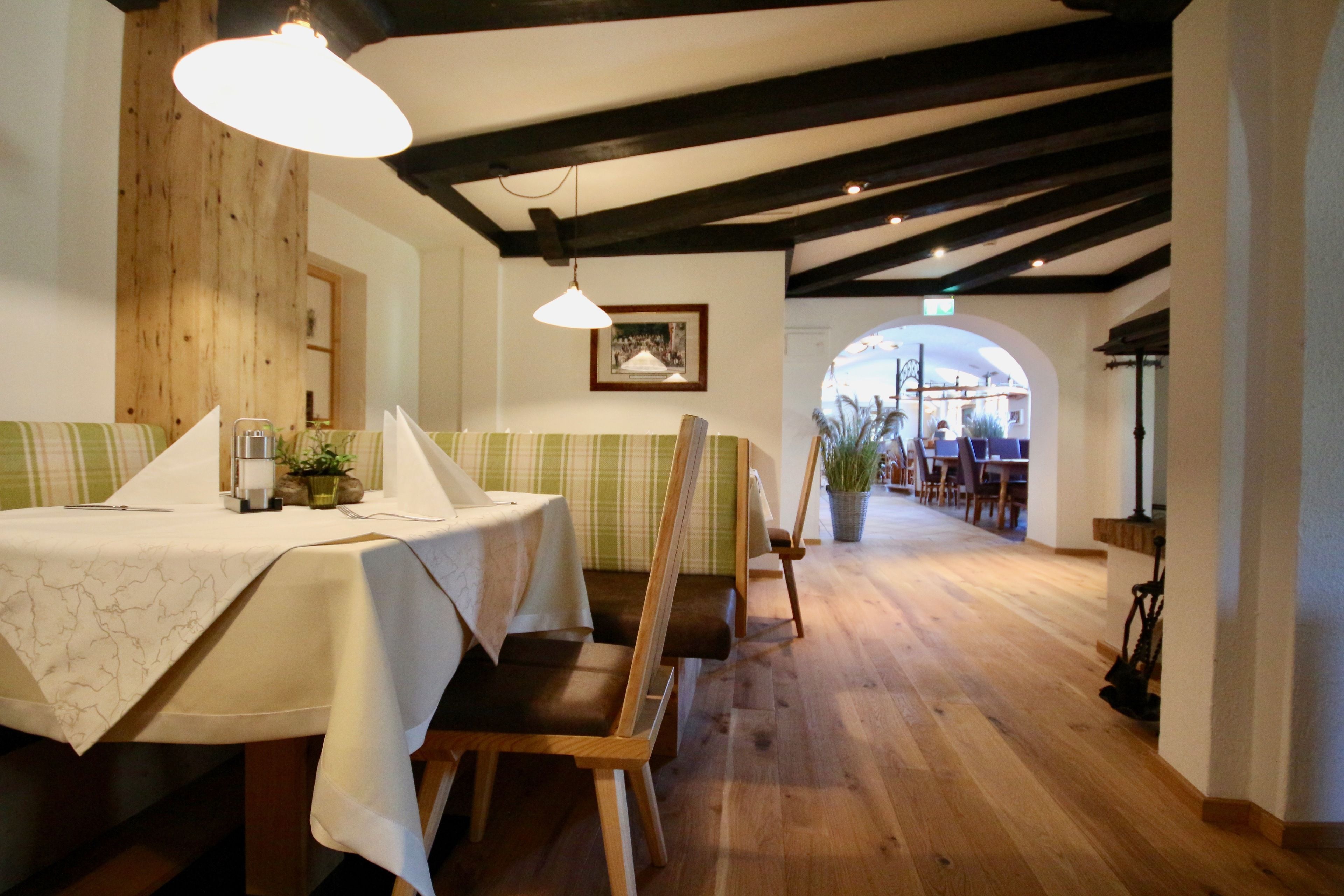 Un restaurant doté de planchers en bois, de tables recouvertes de nappes blanches, de chaises en bois et de luminaires suspendus.