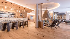 Un espace bar moderne avec des tabourets en bois, un comptoir en pierre et des luminaires suspendus.