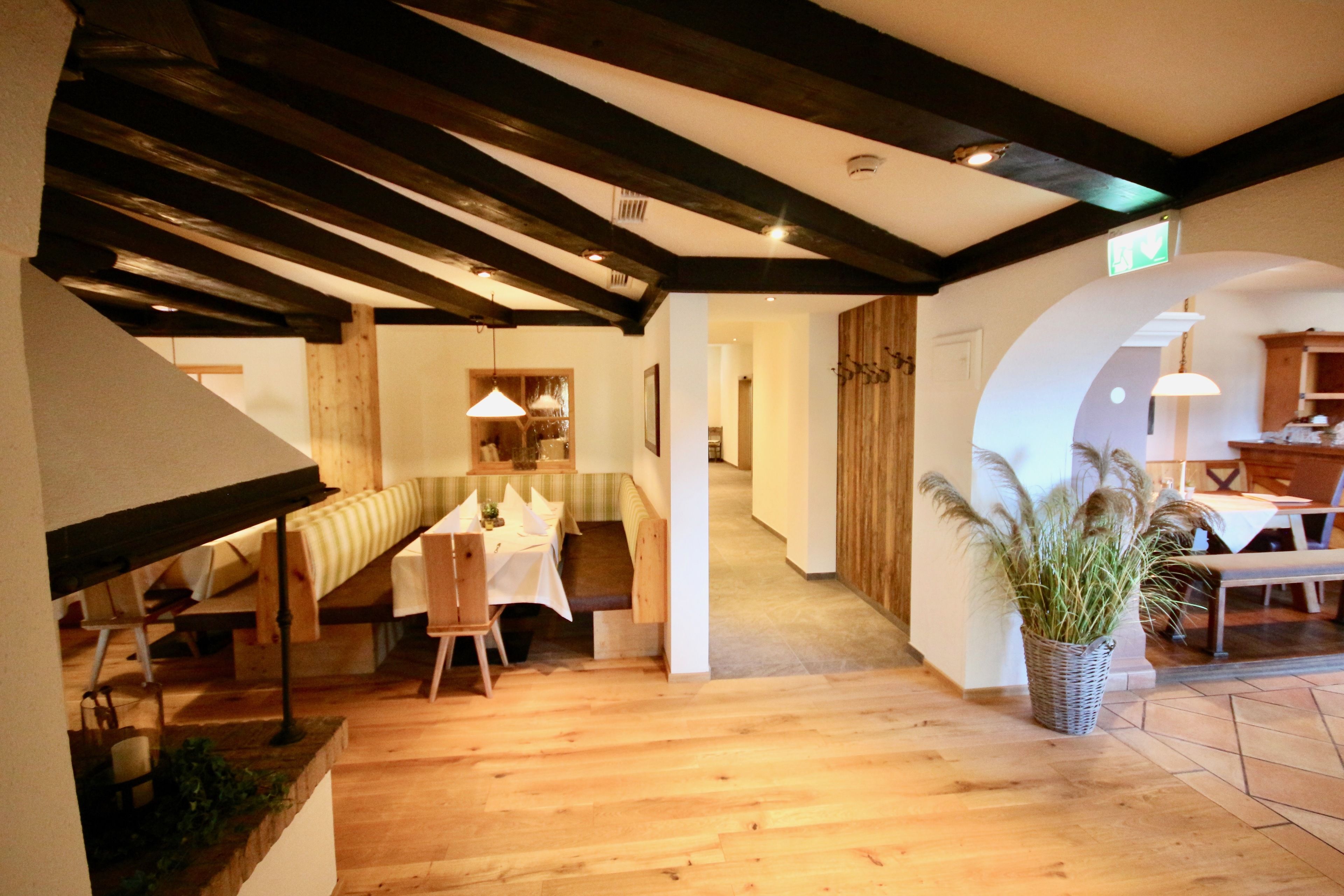 A spacious dining area with a high ceiling and exposed beams, a cozy seating area with a bench, and a potted plant adding greenery.