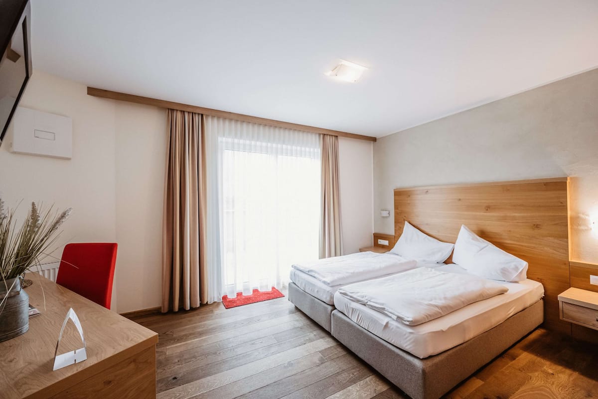 Une chambre d’hôtel comprenant un lit, une table de chevet et un bureau avec une chaise.