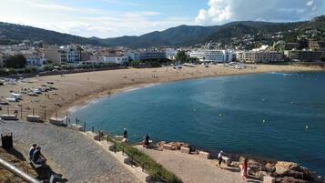 A coastal town with a sandy beach, a promenade, and buildings in the background.