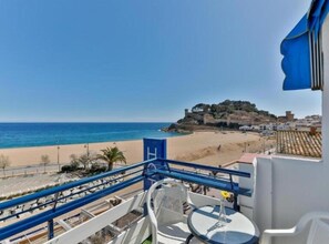A balcony with a view of a beach and a historic hilltop. - Hotel Corisco (Tossa de Mar)