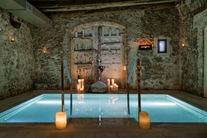 A stone-walled room with a large arched door labeled "FLOTRIUM," a pool with candles, and a sign indicating the room's name. - Mas Salagros Ecoresort & Aire Ancient Baths (Vallromanes)