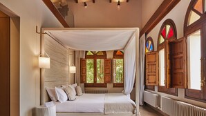 A bedroom with a canopy bed, wooden beams, and a view of greenery through windows. - Mas Salagros Ecoresort & Aire Ancient Baths (Vallromanes)
