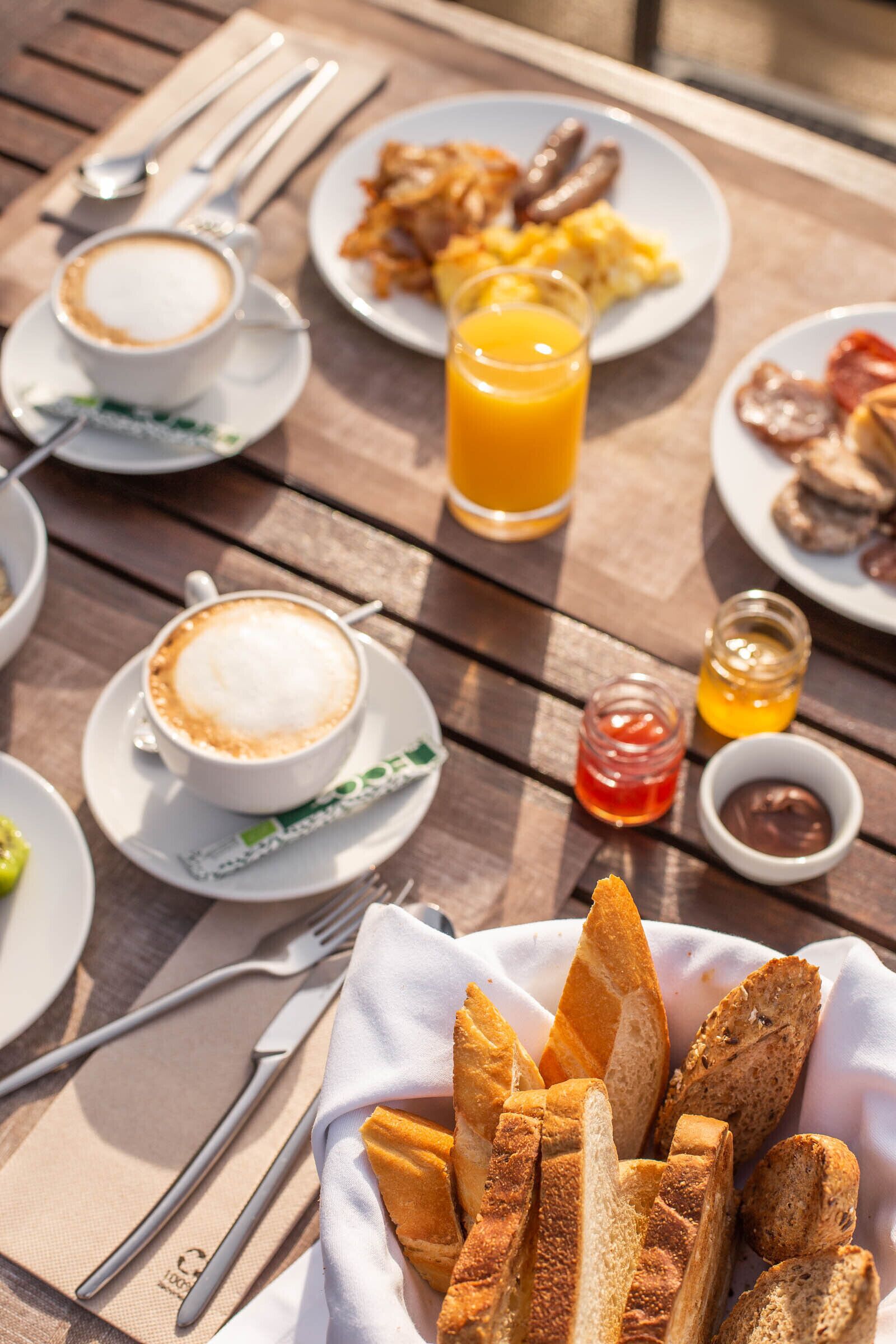 A wooden table with breakfast items including croissants, a coffee cup, and a glass of orange juice.