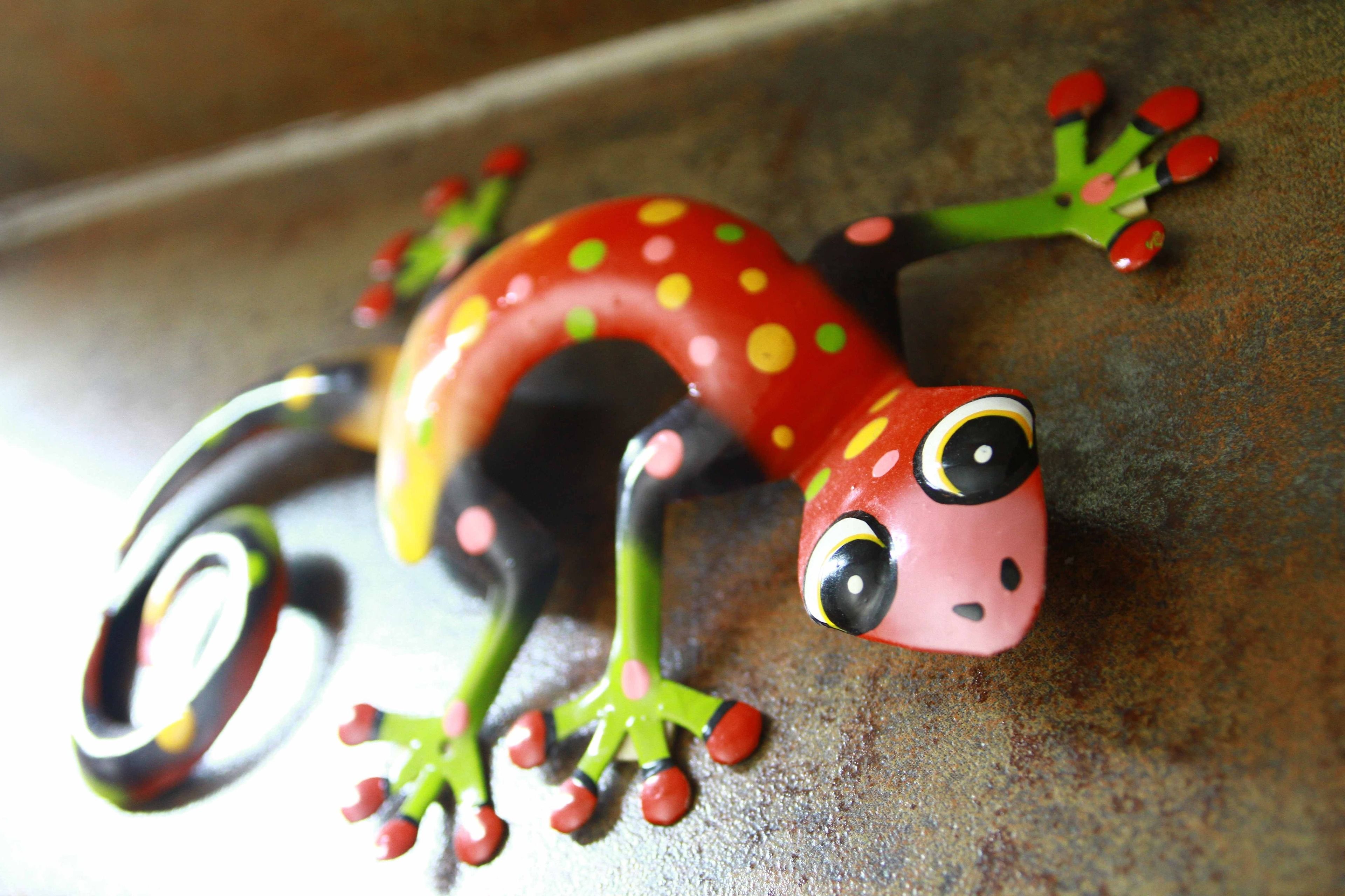 A colorful toy gecko with red spots and yellow eyes.