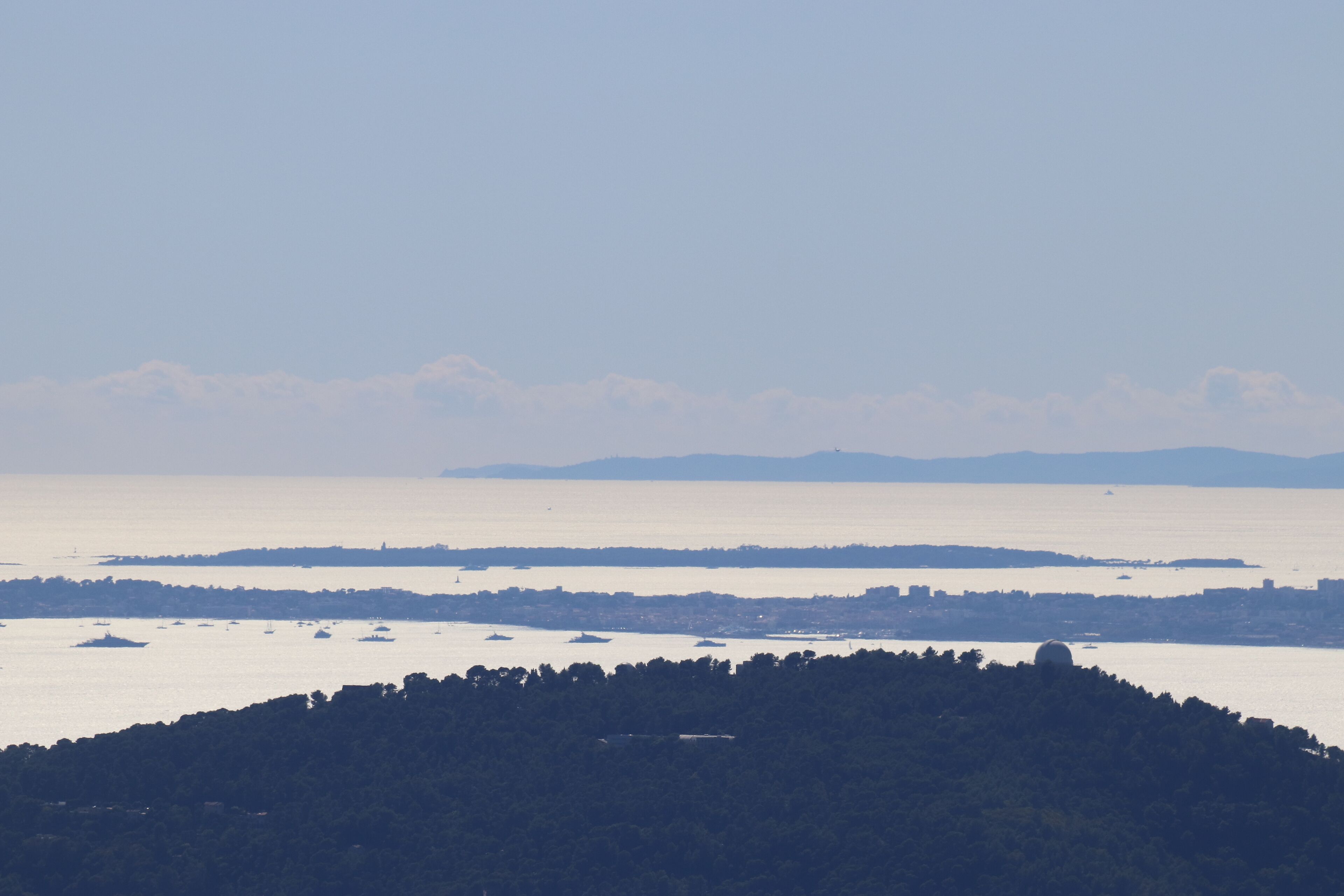Un paysage côtier avec une colline au premier plan et une étendue d’eau en arrière-plan.