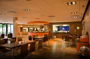 A spacious restaurant with a central counter, multiple seating areas, and a visible kitchen in the background.