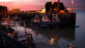 A harbor at dusk with boats docked, a crane, and a building with lights. - Becket Court - University of Kent - Campus Accommodation (Canterbury)