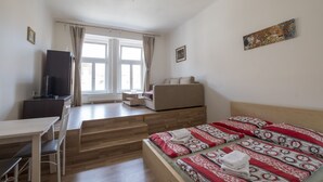 Un dormitorio con cama, escritorio, silla, televisor y sofá.