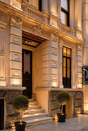 Un bâtiment doté de détails architecturaux raffinés, d’une porte noire et d’une enseigne indiquant « Miniature Hotel ».