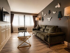 A modern living room with a sofa, a coffee table, and a TV mounted on the wall. - Hotel Miniature (Istanbul)