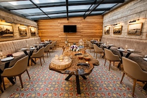 Un restaurante con una mesa de madera central, diversas disposiciones de asientos y un suelo con diseño.