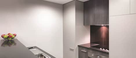 Una cocina moderna con un lavamanos de acero inoxidable, un horno empotrado y una encimera oscura.