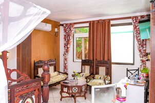 Una habitación tradicional con muebles de madera, una cama con dosel, una mesita con un florero y una ventana con cortinas.