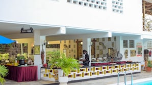 A poolside area with a bar, outdoor seating, and a sign reading "MARULA PALMS".
