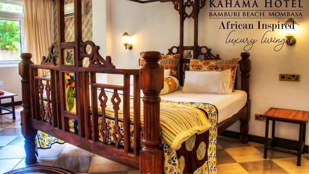 A four-poster bed with intricate wooden carvings, a patterned bedspread, and a nightstand with a lamp.