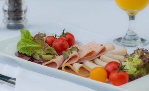 A white rectangular plate with various food items including sliced meats, cherry tomatoes, and leafy greens. - Marriott Hotel Production City, Dubai (Dubai)