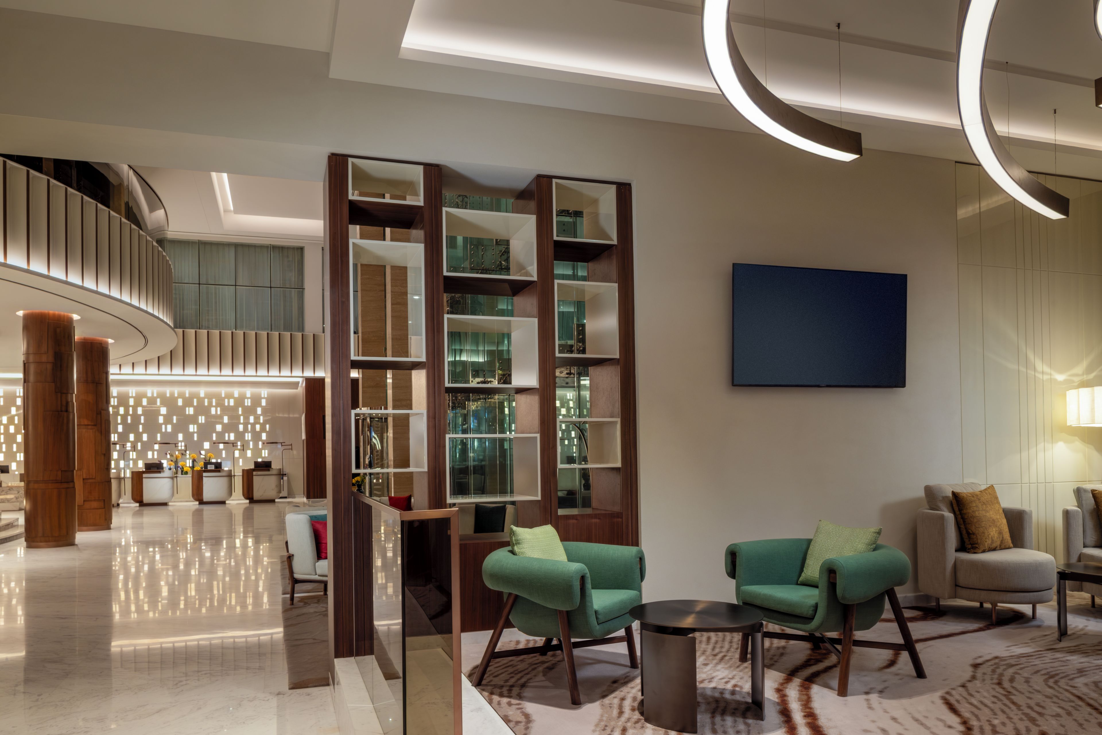 A modern lobby with a reception desk, seating area, and a staircase.