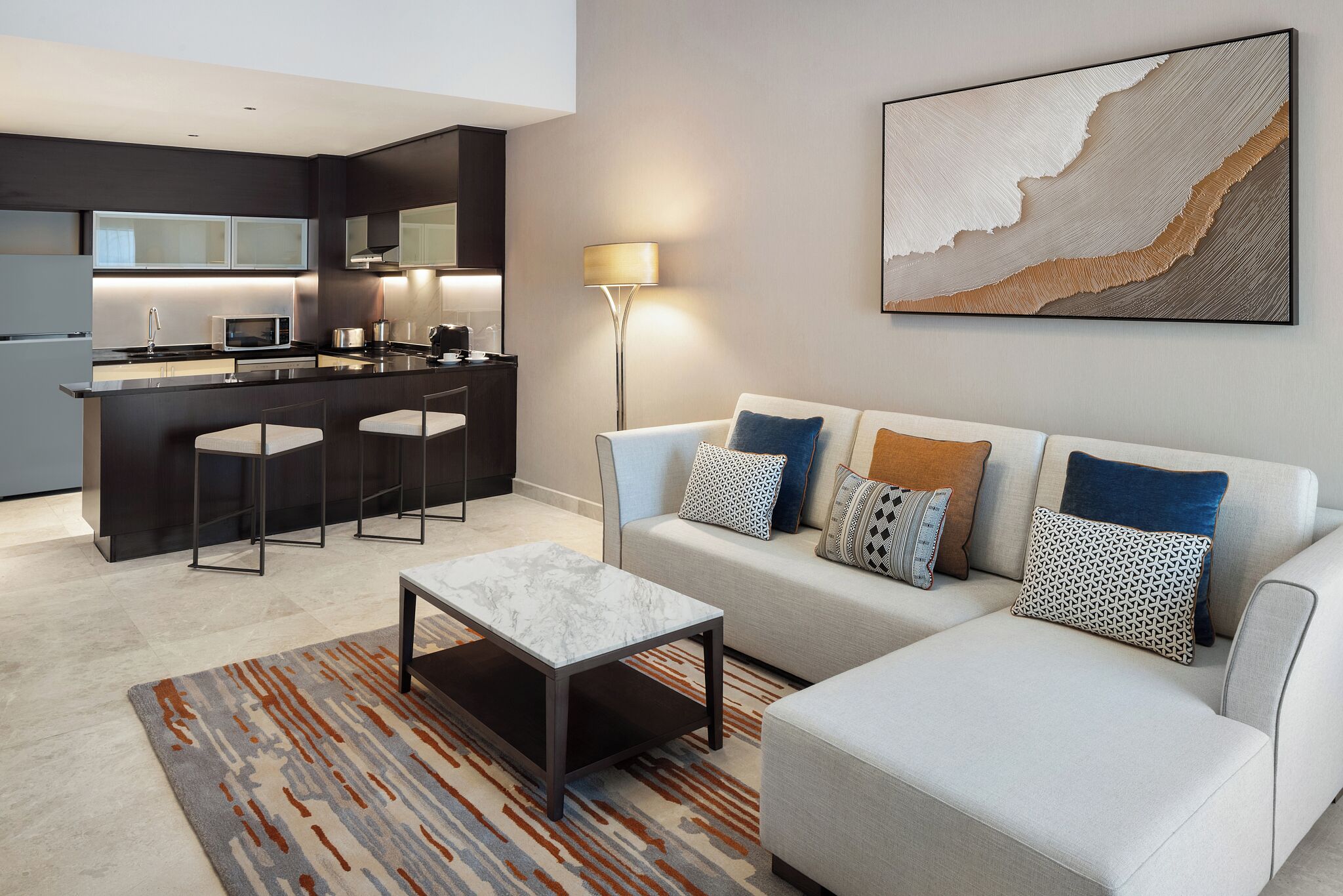 A modern living room with a sofa, coffee table, and a kitchen area with a bar.