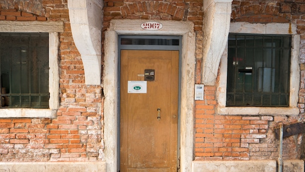 A wooden door with a brass handle, a sign above it, and a number "2967" on the wall. - Backpackers House Venice - Hostel (Venice)