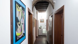 A narrow hallway with a tiled floor, wooden doors, and a framed abstract painting on the left wall. - Backpackers House Venice - Hostel (Venice)